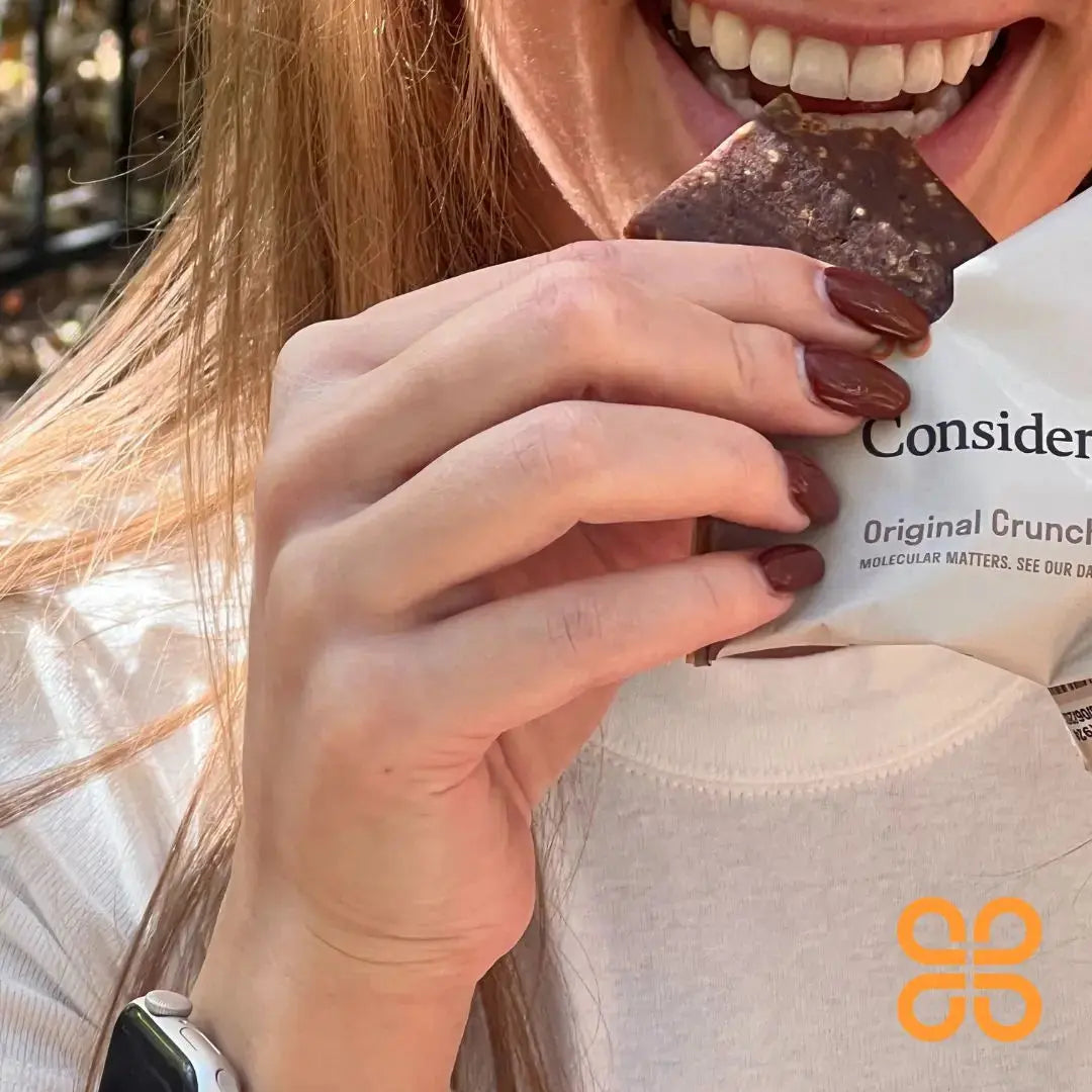 image of a girl eating a Consider This original crunch low histamine protein bar and smiling